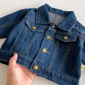 Dettaglio giacca di jeans per bambini, elegante top neonato blu manica lunga bottoni.