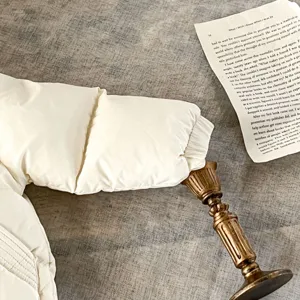 Primer plano detallado de la manga de chaqueta de plumón de bebé blanca, textura de invierno.