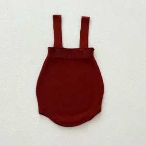 Barboteuse tricotée pour bébé avec bretelles, tissu coton rouge foncé, vue de détail douce.