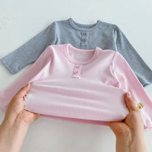 Détail t-shirt manches longues côtelé bébé montrant texture douce et design élastique.