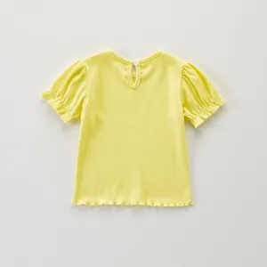 Detalle del top corto de canalé amarillo para niña, borde de volantes y botón en la espalda.