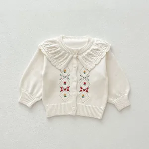 Vue détaillée d'un gilet en tricot blanc pour bébé avec broderie florale et col volanté.