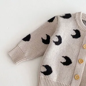 Close-up detail of baby knit cardigan with cute black crescent moon pattern and buttons.