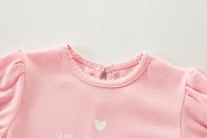 Detalle escote camiseta bebé niña rosa, tejido acanalado, ribete volante, corazón tierno.