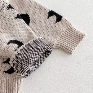 Detail view of baby knitted cardigan sleeve, cute moon pattern, soft cotton fabric texture.