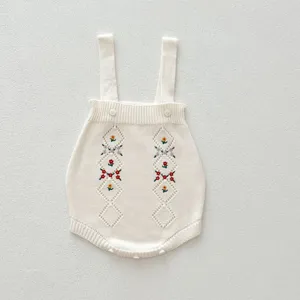 Détail de barboteuse en tricot pour bébé avec broderie florale délicate et coton doux.