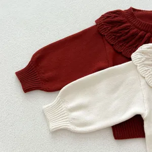 Vue détaillée d'un joli cardigan tricoté pour bébé avec col à volants et manches lanternes.