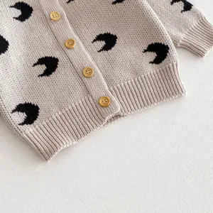 Close-up detail of baby knitted cardigan featuring cute all-over crescent moon pattern and buttons.