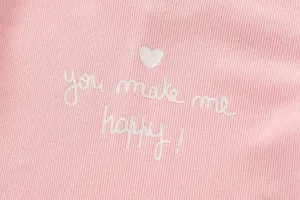 Primer plano detallado del suave tejido de canalé rosa para niña con corazón y texto.