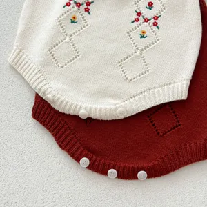 Gros plan détaillé du barboteuse tricoté pour bébé avec broderie florale et losanges.