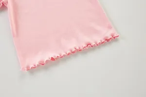 Detalle de camiseta rosa de canalé con borde de lechuga, tela suave, top de niña.