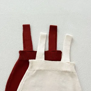 Vue détaillée de barboteuse bébé en tricot doux avec options de couleur crème et rouge.