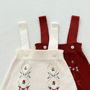 Gros plan détaillé de jolie barboteuse en tricot pour bébé avec broderie florale et ajourée.