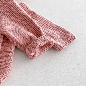 Close-up view of soft pink baby knitted sweater sleeve showing delicate and fine knit texture.