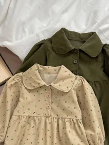 Close-up detail of cute infant corduroy dresses featuring doll collars and floral print.