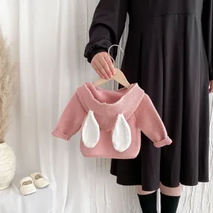 Detailed view of cute baby knit sweater with white bunny ears on back, cozy pink wool fabric.