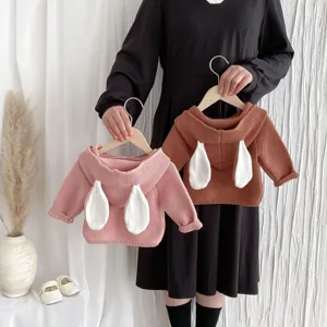 Detail view of infant knitted sweater featuring cute rabbit ear accents and cozy hood design.