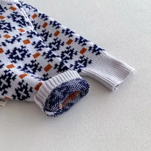 Infant knit sweater sleeve detail, blue and orange geometric pattern, soft texture knit.