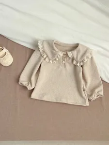 Infant baby girl long sleeve top with lace Peter Pan collar and waffle texture fabric.