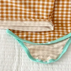 Primo piano sui dettagli della tutina neonato in cotone a quadretti con bottoni e bordo verde menta