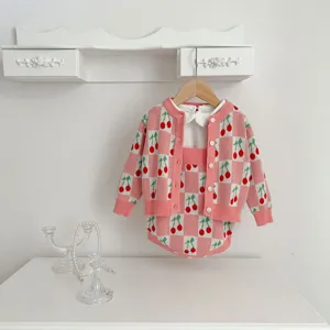 Baby girl knit cardigan and romper set with pink checkerboard cherry jacquard pattern detail.