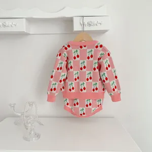 Detailed view of baby pink checkered cherry knit sweater and romper set, cozy and soft.