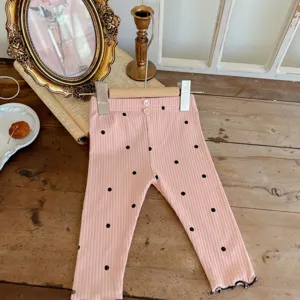 Cute infant baby pink ribbed cotton pants featuring black polka dots and lovely lettuce hem.