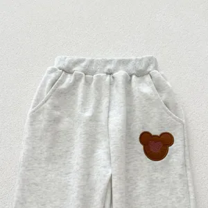 Grey infant sweatpants detail view, soft cotton fabric, elastic waistband and cute bear patch.