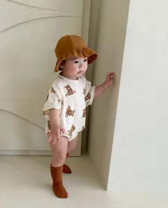 Detailed scene of infant wearing cute all-over bear print romper with brown hat.
