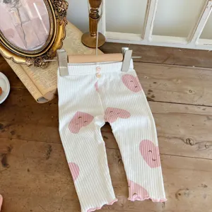 Close-up detail of infant ribbed cotton leggings with cute pink smiling heart prints.