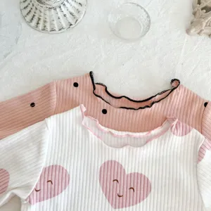 Cute infant ribbed cotton long sleeve top with sweet lettuce edge and smiling heart print detail.