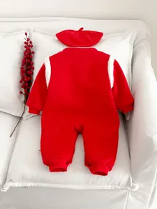 Dettaglio tutina invernale in pile per neonato rossa, abito festivo con cappellino coordinato.