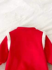 Dettaglio della tutina invernale per neonati in peluche rosso e bianco, body caldo di Capodanno.