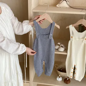 Detailed view of soft knitted baby romper on wooden hanger, cozy aesthetic infant clothing.