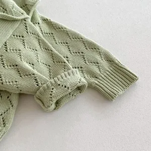 Close-up detail of infant baby girl cotton knit sweater featuring hollow-out diamond pattern.