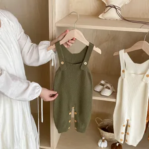 Detailed view of baby knit romper, soft texture with wooden buttons, cozy wooden shelf background display.