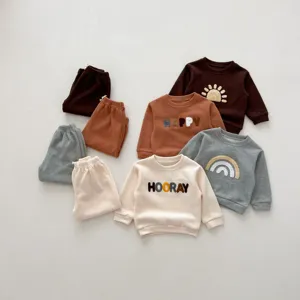 Detailed shot of infant autumn clothing set, featuring soft embroidered typography and cute graphics.