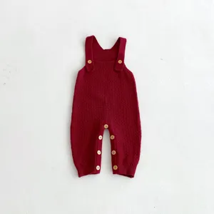 Knitted baby romper jumpsuit detail view showcasing soft texture and cute wooden buttons.