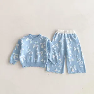 Close-up detail of cute girls knit sweater and bow pants set in light blue color.