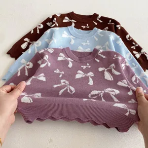 Detailed shot of girls knit sweater hem, showing soft fabric texture and cute bow jacquard pattern.