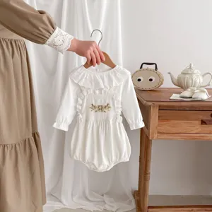 Delizioso body neonata in cotone a maniche lunghe con ricamo floreale e colletto con volant.