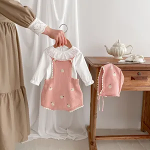 Dettaglio del set tutina lavorato a maglia per neonata con delicati fiori ricamati.