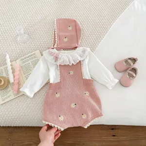 Dettaglio set tutina neonata in maglia con ricamo margherita e cappellino coordinato.