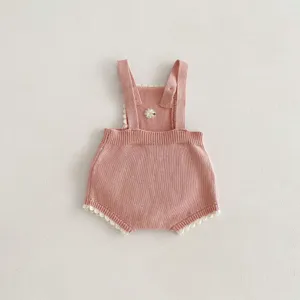 Dettaglio tutina neonata in maglia, pantaloncino con bretelle rosa con ricamo floreale.