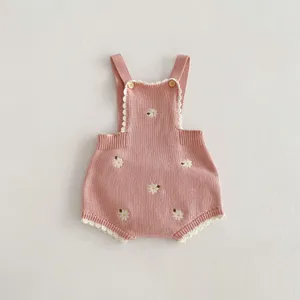 Dettaglio tutina neonato in maglia, ricamo margherita carino, cotone rosa, stile con bretelle.