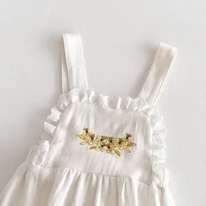 Primo piano di una tutina da neonato con delicato ricamo floreale e dolce bordo in pizzo.