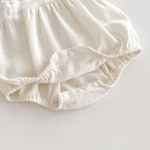 Dettaglio in primo piano della tutina in cotone per neonati con bottoni a pressione e arricciatura.