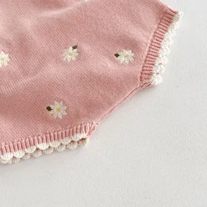 Dettaglio ravvicinato di una graziosa tutina rosa in maglia con ricamo floreale.