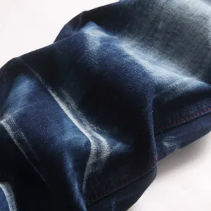 Close-up detail van donkerblauwe gewassen denim stof met vintage vervaging en rode stiksels.