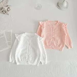 Detailed view of baby girls knit cardigan sweaters in white and pink with delicate ruffle shoulder.
